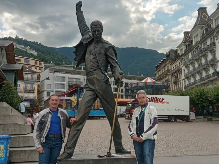 Image of pair on motorcycle holiday, stood next to Freddie Mercury statue